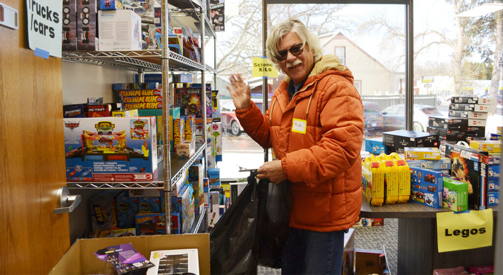 Volunteer at Hope for the Holidays with shelf of toys
