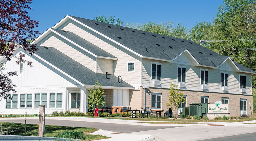 Exterior view of West Creek Apartments building with a green lawn