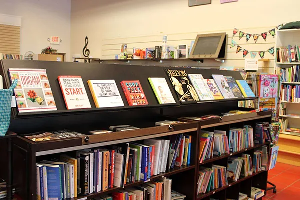 Shelves filled with secondhand books and framed art displayed inside the Local Imports Thrift Store.